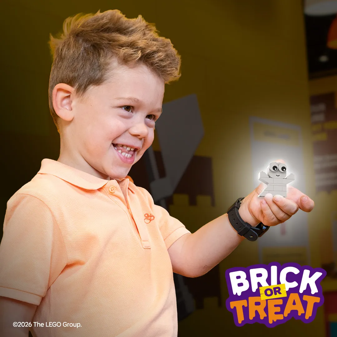 A child holding a LEGO glow in the dark ghost build.