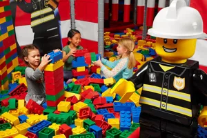 Children playing with large LEGO bricks with LEGO minifigure statue