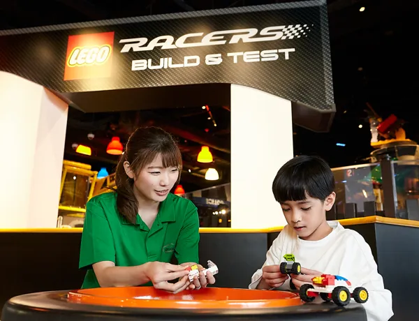alt="「レゴ🄬レーサー ビルド&テストゾーン」でクルマを作る男の子とスタッフ"